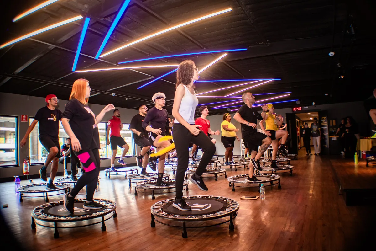 Aula coletiva de jump na Smart Fit, com luzes de neon no teto
